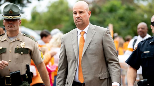 Jeremy Pruitt walks in a suit with an orange tie